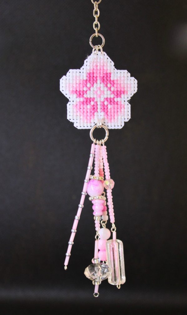 Amuleto bordado a punto de cruz con flor de cerezo rosa hecho a mano